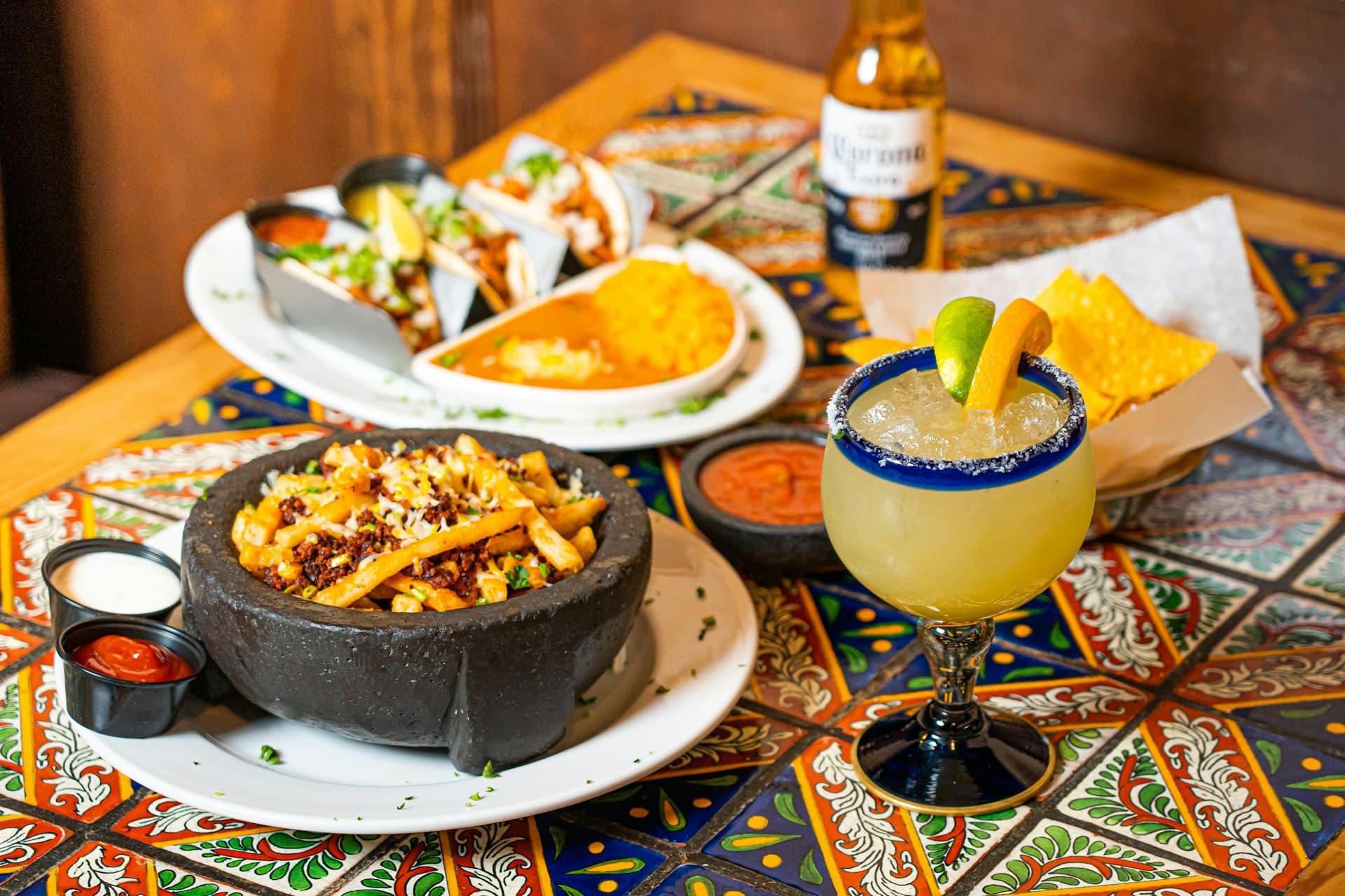 A table filled with tacos, a sizzling molcajete, and a margarita at Fuego y Mesa Mexican Kitchen